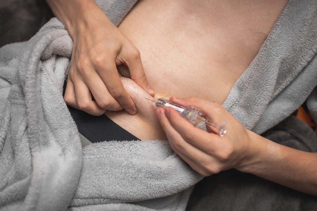 A young man makes an injection at home.